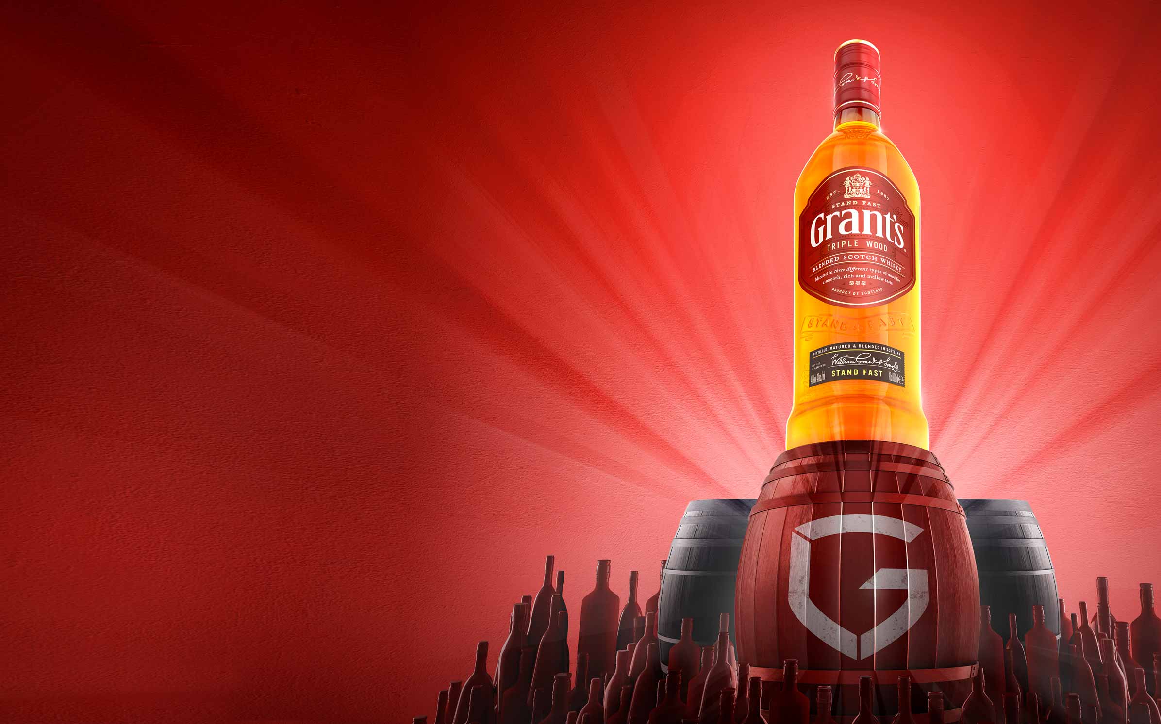 Grant's triple wood whisky bottle on barrel with red background