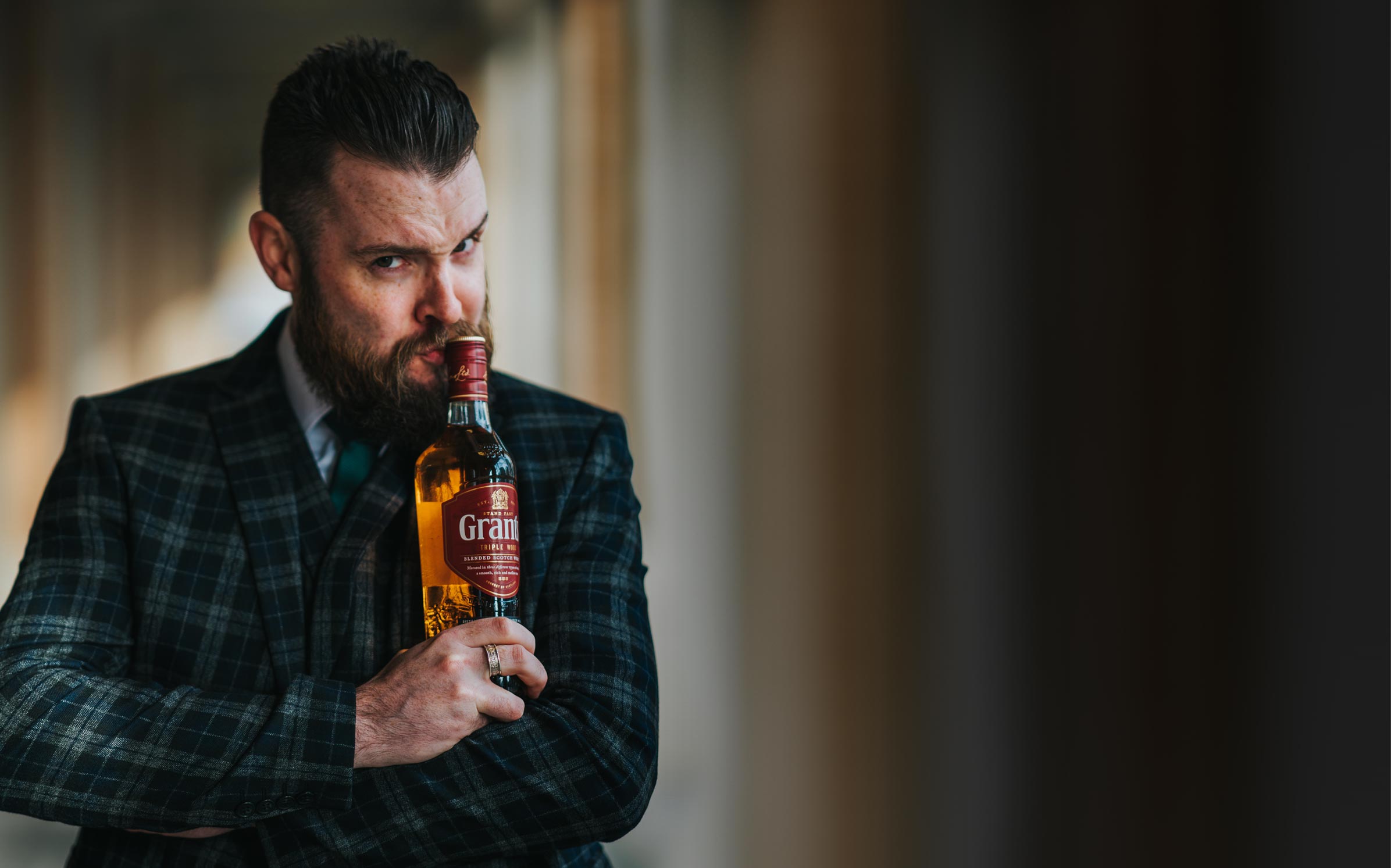 Grant's brand ambassador Danny Dyer wearing a suit and holding a bottle of triple wood 12